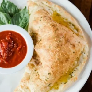 Hand-tossed New York-style calzone with fresh marinara dipping sauce and basil at Jonny's Pizza in Aubrey and Frisco, TX
